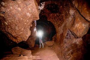 Speleologist journey explores an underground cave, geologist studies hole rock mountain photo