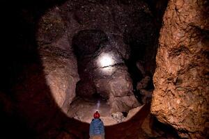 Speleologist explores an journey underground cave, geologist studies hole rock mountain photo