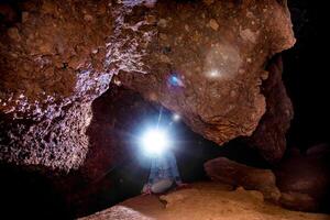Speleologist explores journey an underground cave, geologist studies hole rock mountain photo