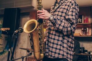 Man play nice wind instrument, musician saxophone performs concert in nightclub bar photo