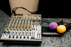 DJ and event host equipment lying on table, music mixer and microphone close up photo