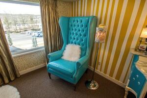 Teal Wingback Chair Near Window With Yellow Striped Walls photo