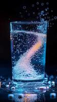 When effervescent tablets are dropped into clear water, they begin to fizz energetically, releasing an array of vibrant bubbles that create a captivating and dynamic swirling pattern in the glass photo