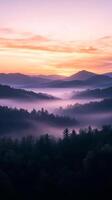 A beautiful sunrise casts warm light across the sky, transforming it into pastel colors. This view illuminates misty mountains and vibrant forests, creating a serene atmosphere for reflection photo