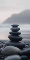 Stacked stones on a tranquil beach with foggy background at dawn photo