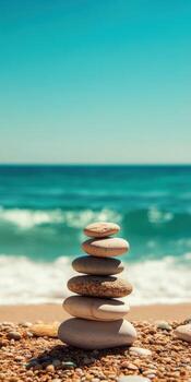 Stacked stones on a beach with waves and clear blue sky photo
