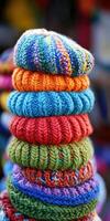 Colorful knitted hats stacked at a festive market in daylight photo