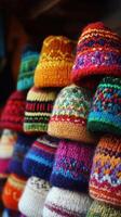 Colorful handmade knitted hats on display at a market during winter photo