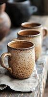 Handmade ceramic mugs on a wooden table in a cozy setting photo
