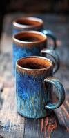 Artistic blue ceramic mugs arranged on a rustic wooden table photo