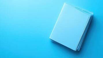 Simple stack of blank white paper on a bright blue background in a well-lit setting photo