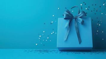 Beautiful blue gift box with a glittery ribbon surrounded by shiny confetti on a vibrant blue background photo