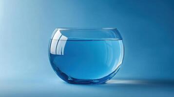 Clear glass bowl filled with water reflecting light against a blue background for a calming effect photo