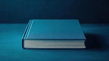 Blue hardcover book resting on a simple wooden table in soft blue light showcasing its elegant design and texture photo