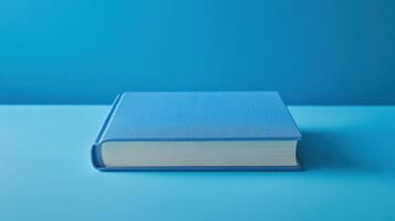 Bright blue hardcover book resting on a light blue surface in a minimalistic setting for studying or reading photo