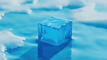 Cube of blue ice sits on a reflective surface surrounded by melted water droplets on a warm day photo