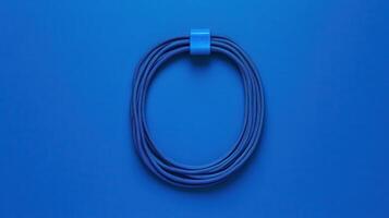 Blue rope coil with a clip displayed on a solid blue background representing simplicity and minimalist design photo