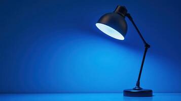 Desk lamp shines brightly against a blue background in a contemporary workspace during evening hours photo