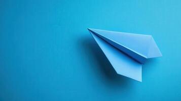 Blue paper airplane resting on a bright blue surface showcasing creativity and simplicity in design and origami craft photo