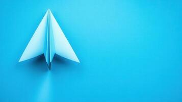 Creative paper airplane takes flight on a vibrant blue surface in a minimalistic setting during daylight photo
