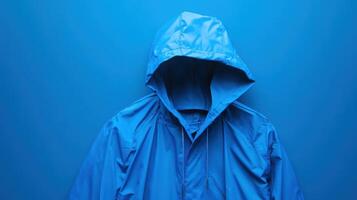 Bright blue rain jacket displayed against a solid blue background creates a striking visual effect in a minimalist setting photo