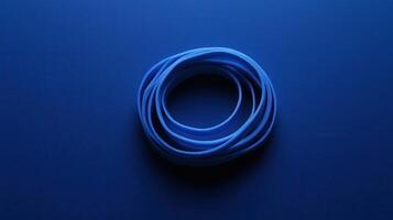 Blue elastic band resting on a deep blue surface captures simple everyday object in striking contrast and calmness photo
