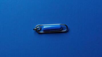Blue safety pin placed on a vibrant blue background highlighting its design and color contrast photo