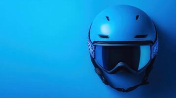 Ski helmet with goggles on a smooth blue background showcasing winter sports gear photo