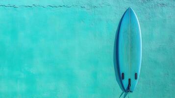 Surfboard rests against vibrant turquoise wall showcasing beach lifestyle elements in a coastal setting photo
