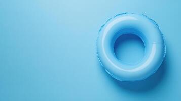 Bright blue inflatable pool ring resting on a solid blue background in a serene and calm setting photo