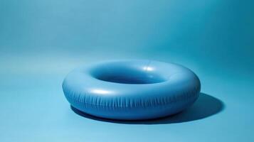 Bright blue inflatable pool ring on a smooth turquoise background for summer fun photo
