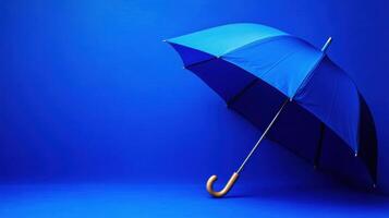Blue umbrella with a wooden handle stands against a vibrant blue background emphasizing simplicity and design aesthetics photo