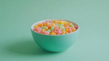 Colorful candy bowl filled with assorted pastel treats on a light green surface photo