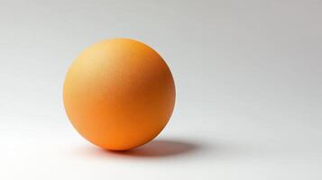 Bright orange sphere resting on a smooth surface showcasing simple design and color contrast in minimalistic style photo