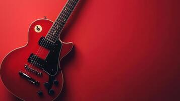 Red electric guitar resting against a vibrant red wall in a studio setting during the evening photo