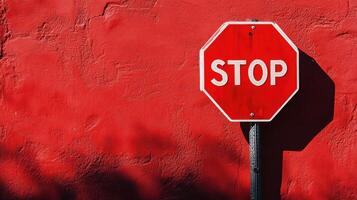 Bright stop sign against a vivid red wall captures attention in an urban setting during daylight hours photo