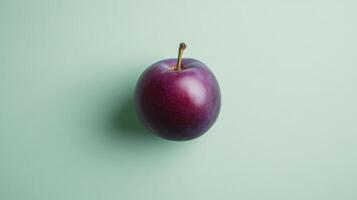 Fresh purple plum on a light green background highlighting its smooth skin and vibrant color photo