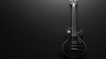 Beautiful black electric guitar hanging against a dark wall showcasing simple yet elegant design and craftsmanship photo