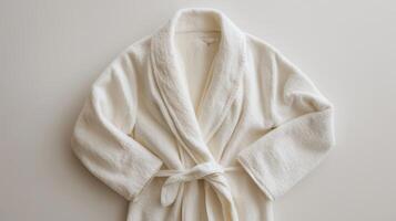 Soft white bathrobe laid flat on a plain surface, showcasing its cozy fabric and simple design for relaxation photo