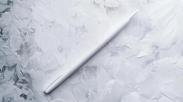 Simple white pencil resting on textured gray surface during creative drawing session in a studio photo