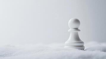 White chess pawn sitting alone on a soft blanket of snow during a quiet winter day photo
