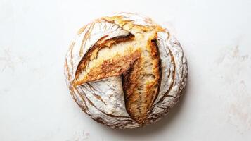Freshly baked artisan bread with a golden crust and unique scoring pattern displayed on a white surface photo