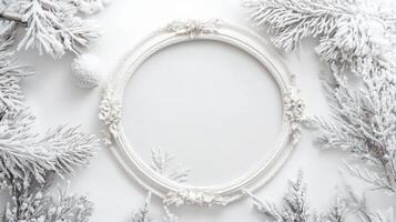Elegant white frame surrounded by frosted pine branches on a light background for winter decor photo