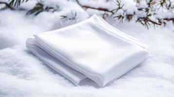 Snow-covered white cloth rests gently on a blanket of fresh snow under evergreen branches during winter days photo