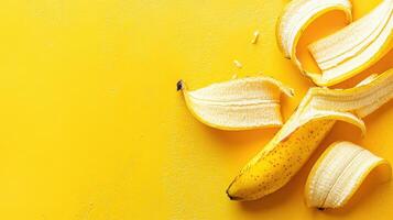 Fresh yellow banana with peels scattered on a bright yellow background showcasing vibrant fruit colors photo
