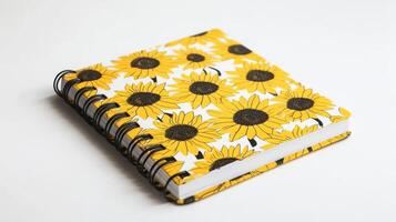 Colorful sunflower-patterned notebook with spiral binding resting on a white surface photo