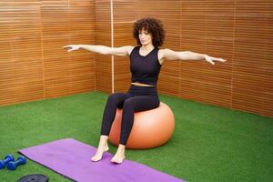A woman is exercising on a stability ball within a modern gym setting that is wellequipped photo