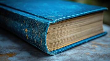 A worn blue book rests on a rustic surface, hinting at its age and inviting exploration photo
