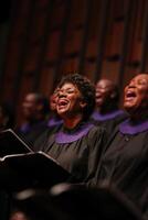 Choir members are singing joyfully, showcasing their enthusiasm and talent while dressed in elegant black robes photo