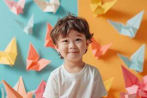 A little boy is smiling in front of a colorful wall of origami birds photo